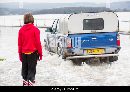 Eine Autofahrer fährt durch Hochwasser auf der Straße bei Storth an der Mündung der Kent in Cumbria, UK, während der Januar 2014 Stürme Stockfoto