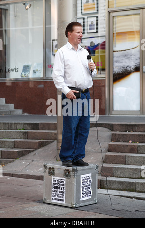 Ein Mann, der auf einer Box steht und mit einem Mikrofon das Evangelium auf der Buchanan Street, Glasgow City Centre, Schottland, Großbritannien predigt Stockfoto