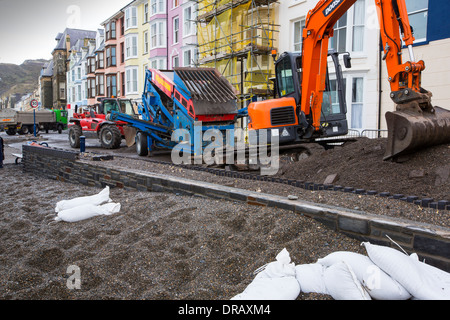 Nach einer Woche der Springfluten, Sturmfluten und Sturmwinde Kraft hat die Strandpromenade von Aberystwyth in Wales, mit Millionen von Pfund Schaden verwüstet. Die brechenden Wellen schlug ein großes Loch in den Deich und ist zusammengebrochen Aberystwyths kultigen, viktorianischen Promenade Unterschlupf, die seit über 100 Jahren stehen geblieben. Dieses Bild entstand auf Mittwoch, 8. Januar 2014, der Tag begann der Rat, zu versuchen, und deaktivieren Sie die Tausende von Tonnen Schutt Strand Meer Offroad. Stockfoto