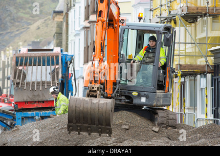 Nach einer Woche der Springfluten, Sturmfluten und Sturmwinde Kraft hat die Strandpromenade von Aberystwyth in Wales, mit Millionen von Pfund Schaden verwüstet. Die brechenden Wellen schlug ein großes Loch in den Deich und ist zusammengebrochen Aberystwyths kultigen, viktorianischen Promenade Unterschlupf, die seit über 100 Jahren stehen geblieben. Dieses Bild entstand auf Mittwoch, 8. Januar 2014, der Tag begann der Rat, zu versuchen, und deaktivieren Sie die Tausende von Tonnen Schutt Strand Meer Offroad. Stockfoto