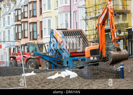 Nach einer Woche der Springfluten, Sturmfluten und Sturmwinde Kraft hat die Strandpromenade von Aberystwyth in Wales, mit Millionen von Pfund Schaden verwüstet. Die brechenden Wellen schlug ein großes Loch in den Deich und ist zusammengebrochen Aberystwyths kultigen, viktorianischen Promenade Unterschlupf, die seit über 100 Jahren stehen geblieben. Dieses Bild entstand auf Mittwoch, 8. Januar 2014, der Tag begann der Rat, zu versuchen, und deaktivieren Sie die Tausende von Tonnen Schutt Strand Meer Offroad. Stockfoto