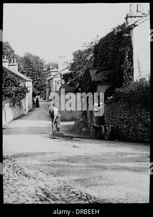 Straßenszene, Beetham, Cumbria (dann Westmorland), Lake District, England, im Jahre 1906. Mann die Straße fegen. Übernommen aus einem Objektträger Laterne. Stockfoto