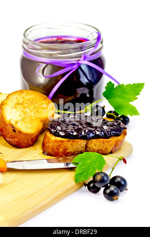 Scheiben geröstetes Brot, ein Glas mit schwarzen Johannisbeeren Marmelade, Messer auf dem Brett isoliert auf weißem Hintergrund Stockfoto