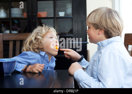 Brüder mit Orangenfrucht am Küchentisch spielen Stockfoto