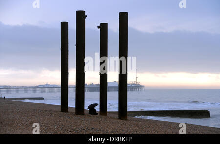 Eine Person sitzt unter einem Regenschirm Ausblick auf das Meer von der West Pier in Brighton Beach im Nieselregen und frühen Morgennebel UK Stockfoto