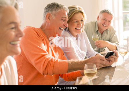 Ältere Ehepaare, tranken Wein und Blick auf Handy Stockfoto