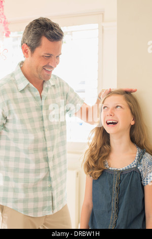 Vater Mess Tochter Höhe an Wand Stockfoto