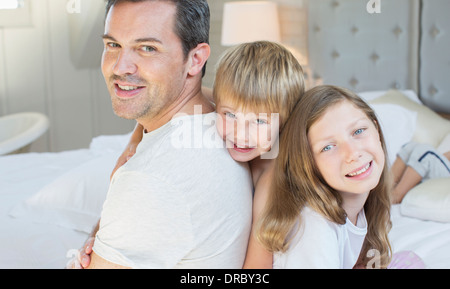 Vater und Kinder entspannend auf Bett Stockfoto