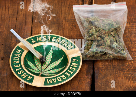 Aschenbecher mit Amsterdam Zeichen und eine große Plastiktüte des Unkrauts auf hölzernen Hintergrund gemeinsame Marihuana rauchen Stockfoto