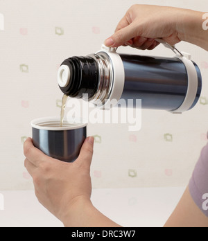 Gießen heißen Tee aus der Thermoskanne in Tasse Stockfoto