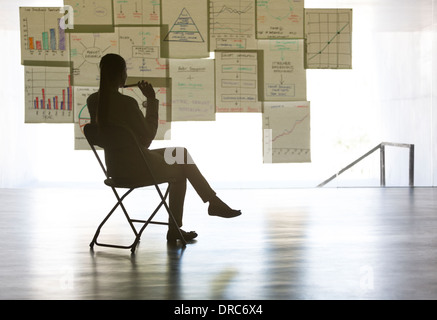 Geschäftsfrau, die studieren, Diagramme und Grafiken auf der Wand im Büro Stockfoto