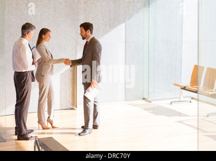 Geschäftsleute Händeschütteln im sonnigen Büro lobby Stockfoto