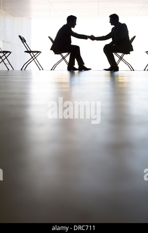 Silhouette der Geschäftsleute Händeschütteln im Büro Stockfoto