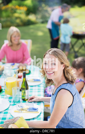 Am Tisch im Hinterhof lächelnde Frau Stockfoto