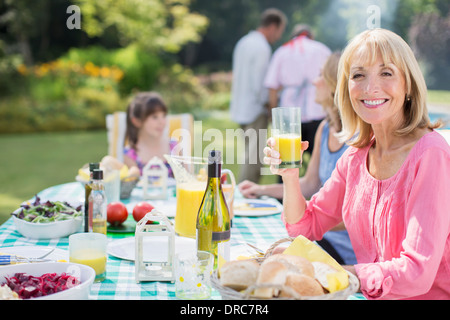 Lächelnde Frau genießen Mittagessen am Tisch im Hinterhof Stockfoto