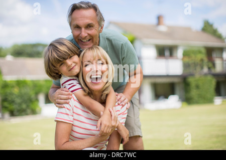 Großeltern und Enkel umarmt im Hinterhof Stockfoto