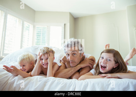 Vater und Kinder entspannend auf Bett Stockfoto