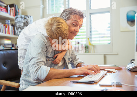 Umarmt arbeitenden Vater des jungen Stockfoto