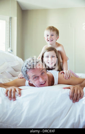Vater und Kinder spielen am Bett Stockfoto
