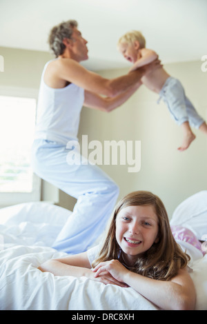 Vater und Kinder spielen am Bett Stockfoto