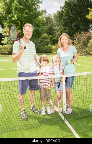 Familie lächelnd zusammen auf Rasentennisplatz Stockfoto