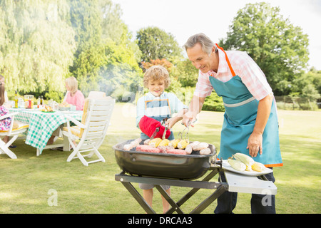 Großvater und Enkel grillen Fleisch und Mais auf Grill Stockfoto