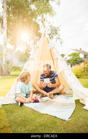 Vater und Sohn mit digital-Tablette im Tipi im Hinterhof Stockfoto