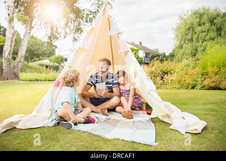Vater und Kinder entspannend im Tipi im Hinterhof Stockfoto