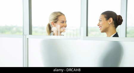 Geschäftsfrauen reden hinter eine halbe Wand im Büro Stockfoto