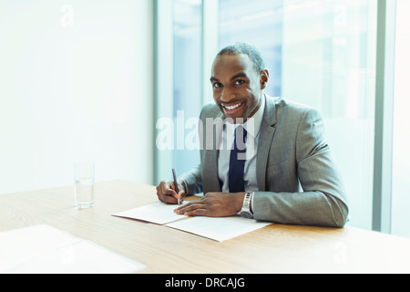 Geschäftsmann lächelnd am Konferenztisch Stockfoto