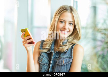 Frau mit Handy am Fenster Stockfoto