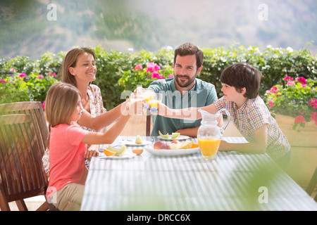 Familie Toasten Orangensaft Gläser am Tisch im Garten Stockfoto