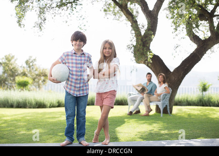 Bruder und Schwester mit Volleyball im Hinterhof Stockfoto