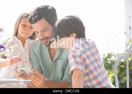 Vater und Kinder mit Handy im freien Stockfoto