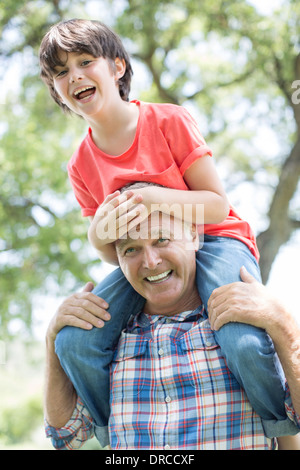 Großvater mit Enkel auf Schultern im freien Stockfoto