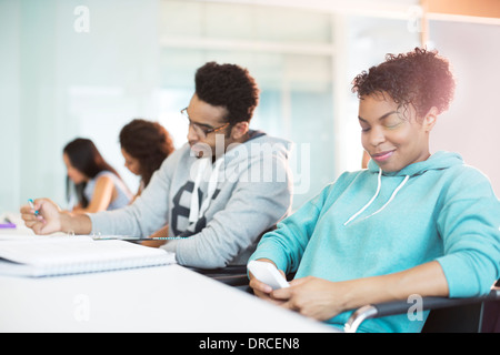 Uni-Student mit Handy im Klassenzimmer Stockfoto