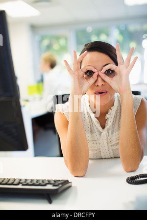 Geschäftsfrau, die Grimasse am Schreibtisch im Büro Stockfoto