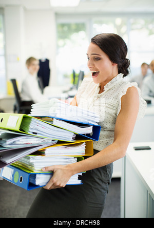Geschäftsfrau, die Ordner im Büro tragen Stockfoto