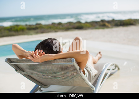 Frau im Liegestuhl am Pool Sonnenbaden Stockfoto