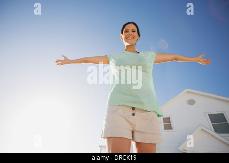 Frau lächelnd mit ausgestreckten gegen blauen Himmel Stockfoto