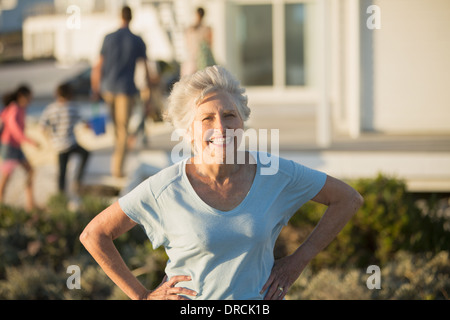 Ältere Frau lächelnd mit Hände auf den Hüften im freien Stockfoto