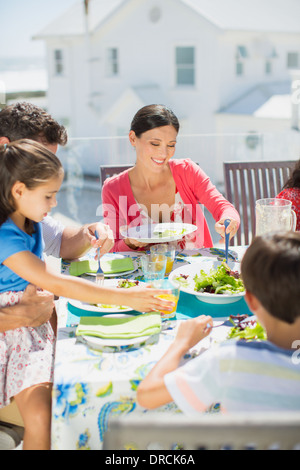 Familie beim Mittagessen am Tisch auf der sonnigen Terrasse Stockfoto