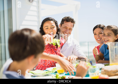 Familie beim Mittagessen am Tisch auf der sonnigen Terrasse Stockfoto