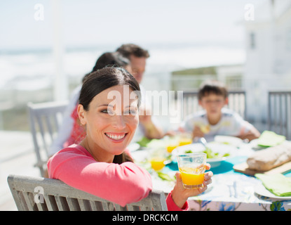 Frau trinkt Orangensaft am Tisch auf der sonnigen Terrasse Stockfoto