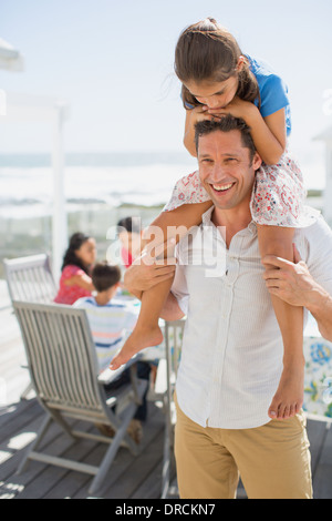 Vater mit Tochter auf Schultern auf sonnigen Terrasse Stockfoto