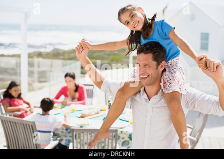 Vater mit Tochter auf Schultern auf sonnigen Terrasse Stockfoto