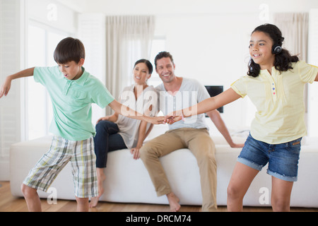 Eltern beobachten, Tochter und Sohn im Wohnzimmer tanzen Stockfoto