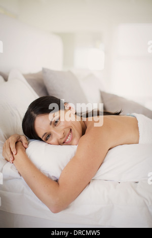 Frau umarmt Kissen auf Bett Stockfoto