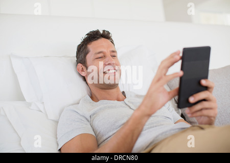 Mann mit digital-Tablette im Bett Stockfoto