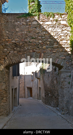 Eine alte Brücke über eine gepflasterte Straße in der historischen Altstadt Caunes-Minervios, Südfrankreich. Stockfoto